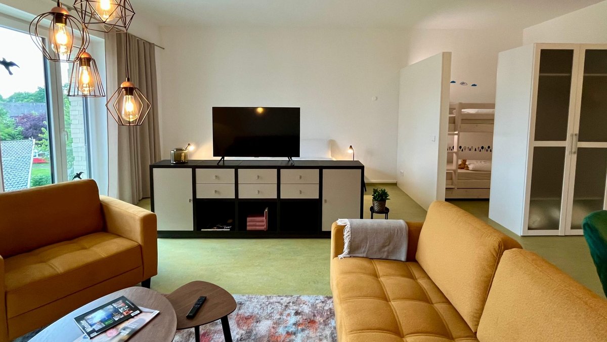 Wohnzimmer mit gelben Sofas und TV Board 